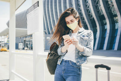 Portrait of young woman standing against building