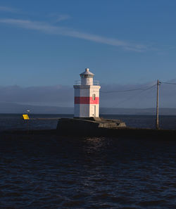 Lighthouse by sea against sky