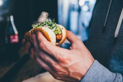 Cropped image of man eating hot dog