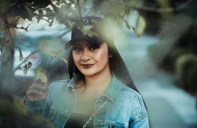 Portrait of young woman in cap by tree