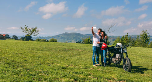 Young couple taking a selfie with a motorcycle outdoors