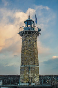 Low angle view of lighthouse by building against sky