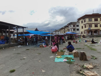 People at market in city against sky