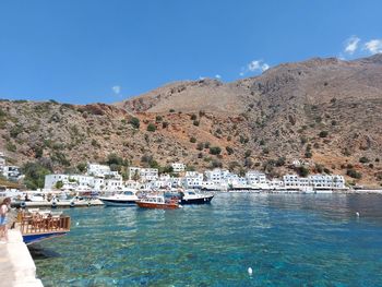 Buildings by sea against clear blue sky