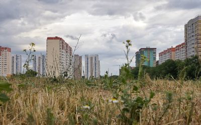 View of buildings in field against cloudy sky