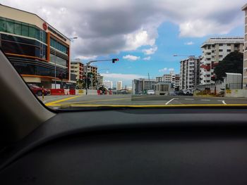 Road by buildings seen through car windshield