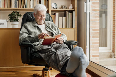 Smiling man reading book at home