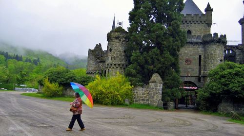 Rear view of woman walking with umbrella in front of the löwenburg castle in germany