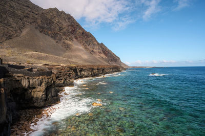 Scenic view of sea and mountains against sky