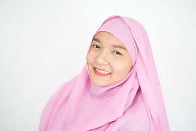 Portrait of a smiling young woman against white background