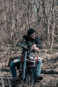 Full length of mid adult man sitting on motorcycle in forest