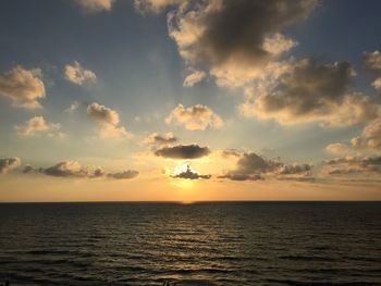 Scenic view of sea against cloudy sky during sunset