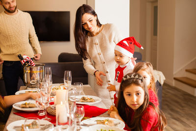 Cheerful family sitting by dining table at home
