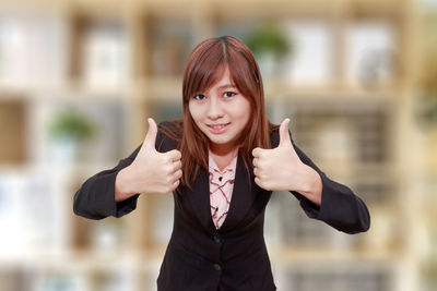 Portrait of businesswoman showing thumbs up sign