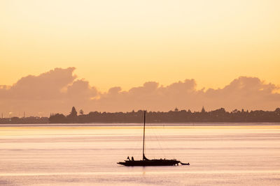 Omokoroa channel at sunset. silhouette of sailboat.