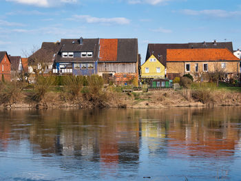 Buildings by river against sky