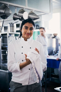 Portrait of confident female chef wiping her hands with napkin in kitchen