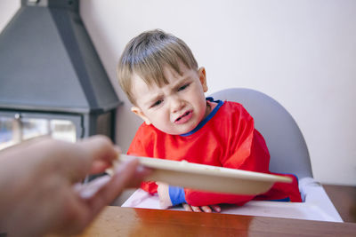 Cute boy crying while sitting on high chair