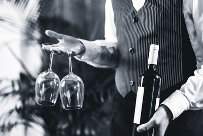 Midsection of bartendar serving wine in bar