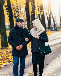 Smiling couple walking on road in park during autumn