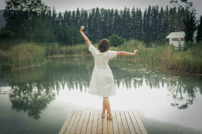 Rear view of woman standing by lake