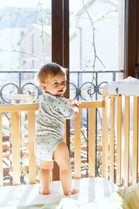 Rear view of cute baby girl standing at home