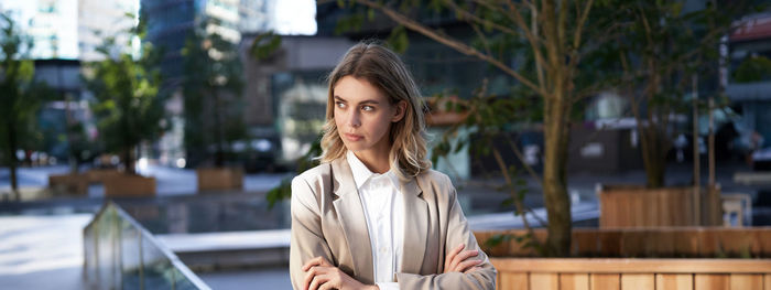 Portrait of young woman looking away while standing outdoors