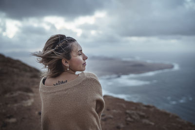 Woman looking at sea shore against sky