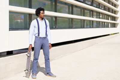 Young man looking away while standing against wall