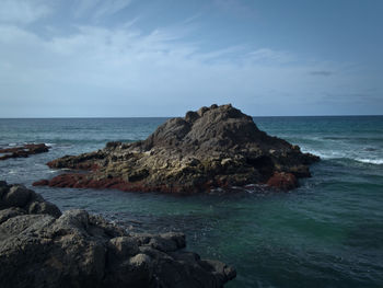 Scenic view of rocks on beach against sky