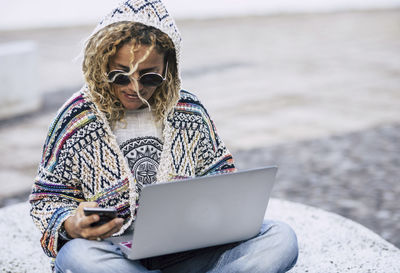 Midsection of woman using mobile phone while sitting outdoors