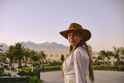 Portrait of woman wearing hat standing against clear sky