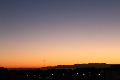 Silhouette buildings against clear sky during sunset