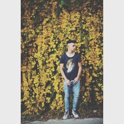 Full length of young man standing on autumn leaves