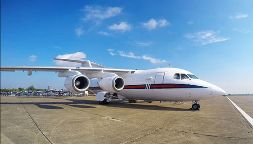 Airplane on airport runway against sky