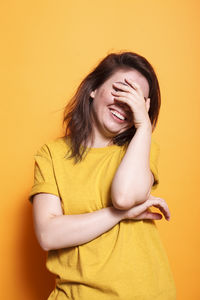 Portrait of young woman against yellow background