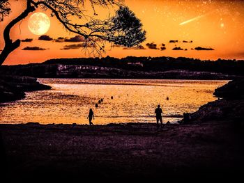 Silhouette people on beach against sky during sunset