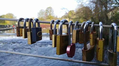 Close-up of padlocks on railing against river