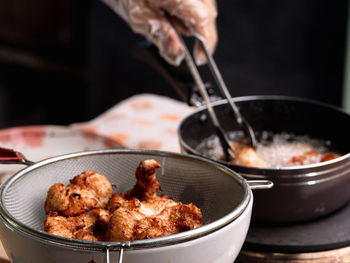 Close-up of hand holding meat in cooking pan