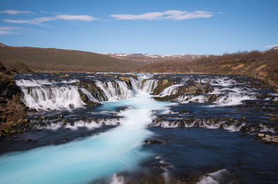 Scenic view of waterfall against sky