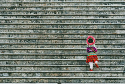 Rear view of girl standing against wall