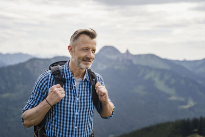 Smiling male backpacker hiking on mountain