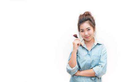 Portrait of young woman using smart phone against white background