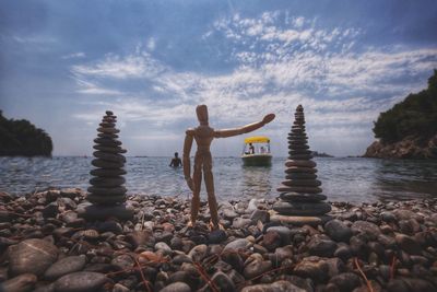 Man on rocks by sea against sky