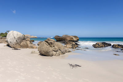 Rocks on beach against clear blue sky