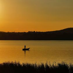 Silhouette boat in lake against sky during sunset