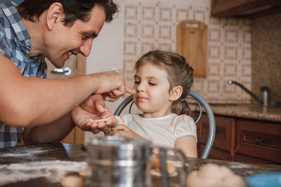 Cheerful father and daughter preparing food at home