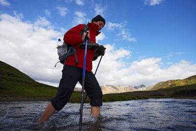 Young woman crossing river on the laugavegur hiking trail