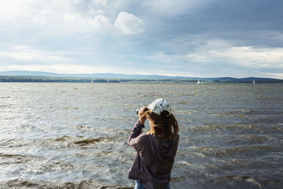 Rear view of woman looking at sea against sky