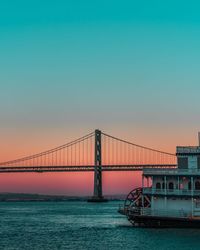 Bridge over sea against clear sky during sunset